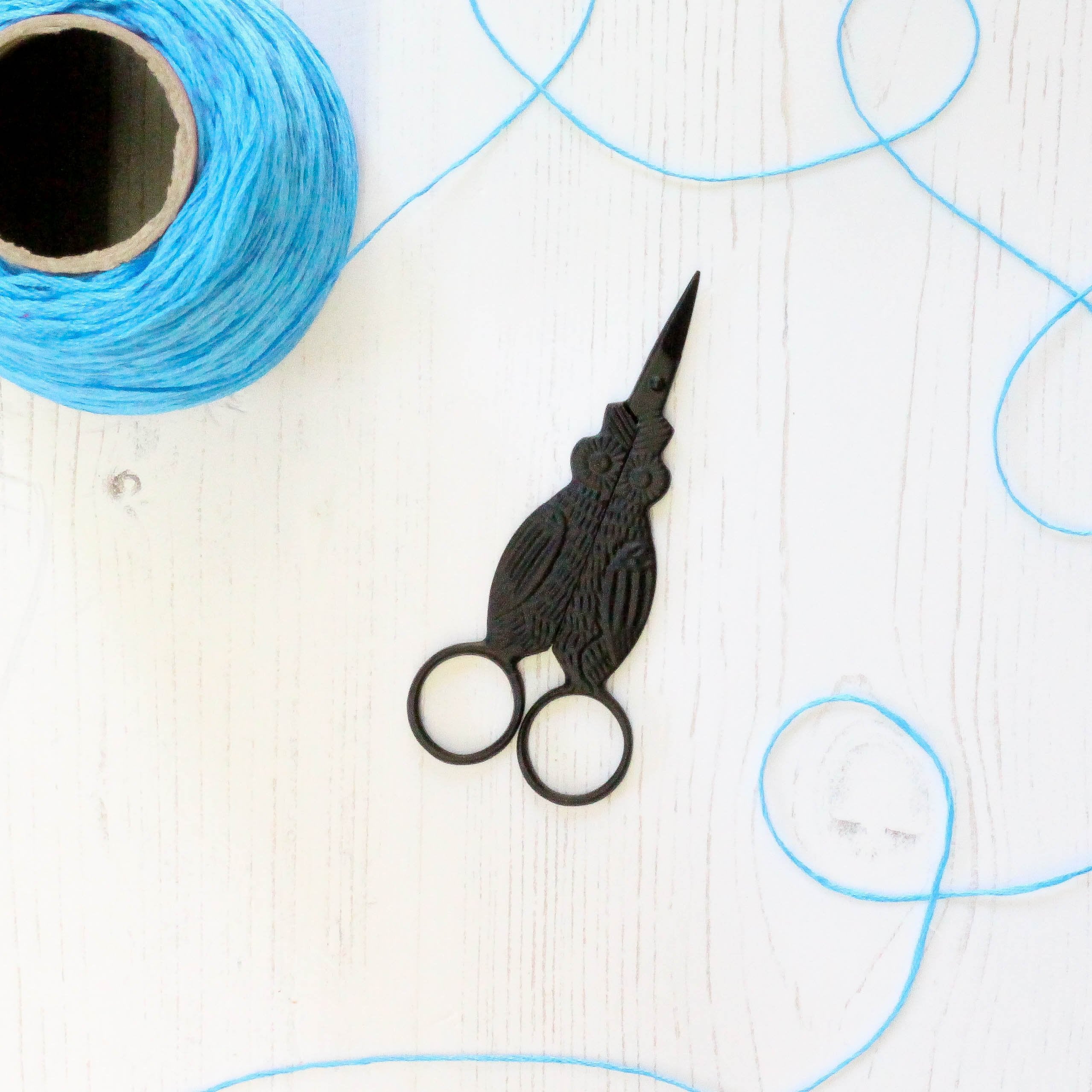 Black Owl Embroidery Scissors closed with thread