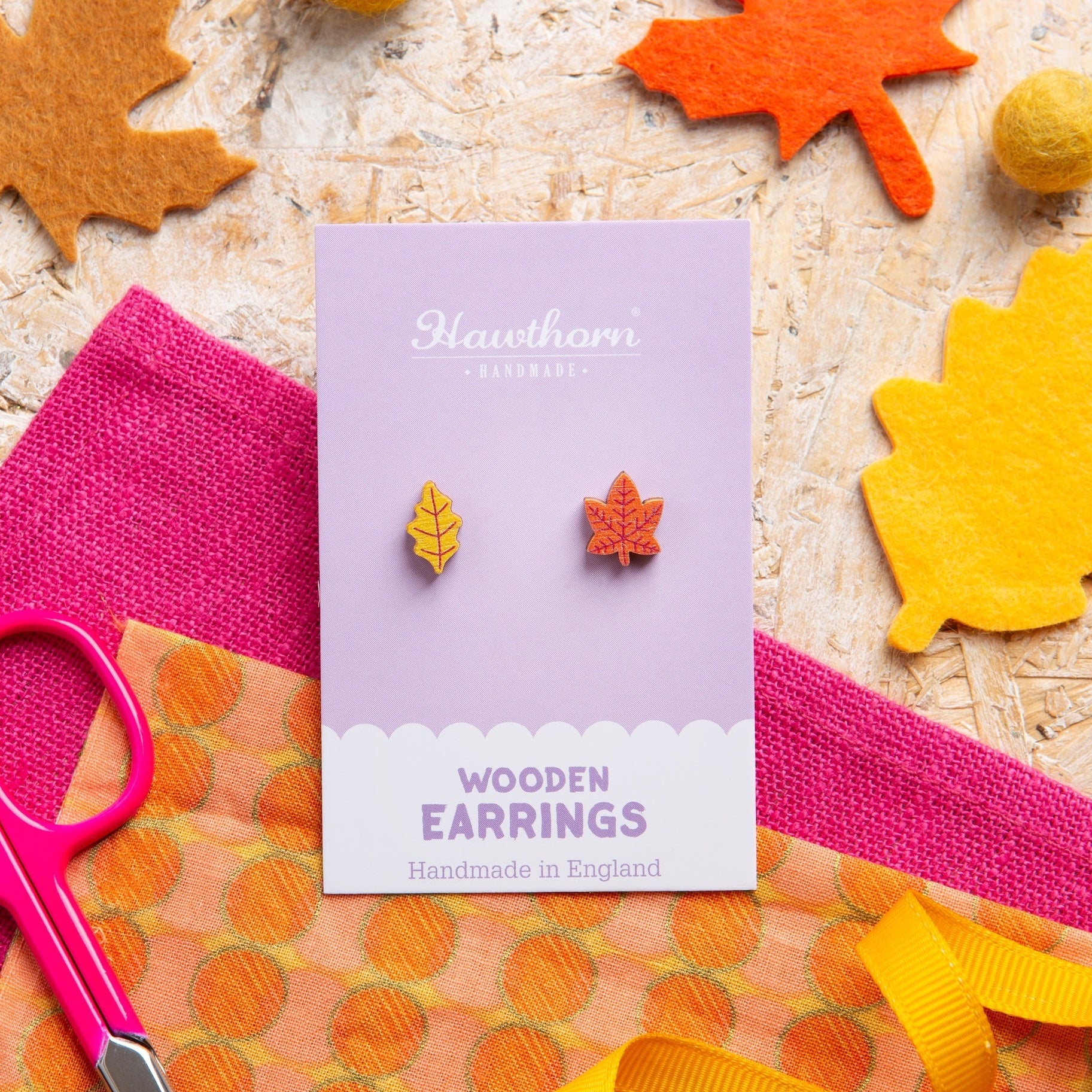 Leaf wooden earrings on a card with fall-themed decorations including leaves and ribbons.