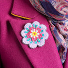 Beatrix flower brooch worn on lapel of fuchsia coat.