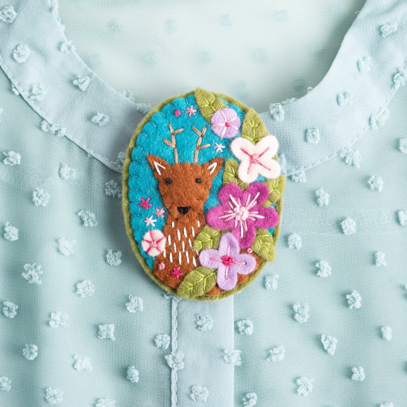 Deer brooch worn on mint green top.