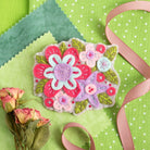 Gertrude flower brooch felt craft kit displayed on green background.