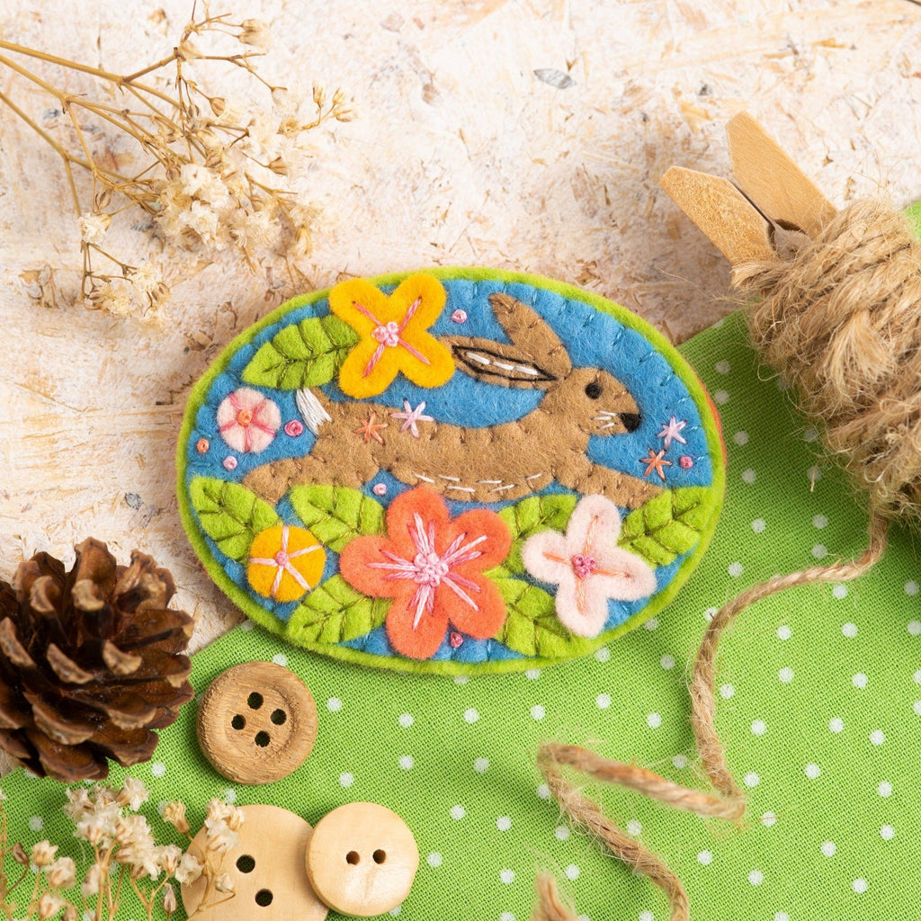 Hare brooch displayed on wooden background with nature themed props.