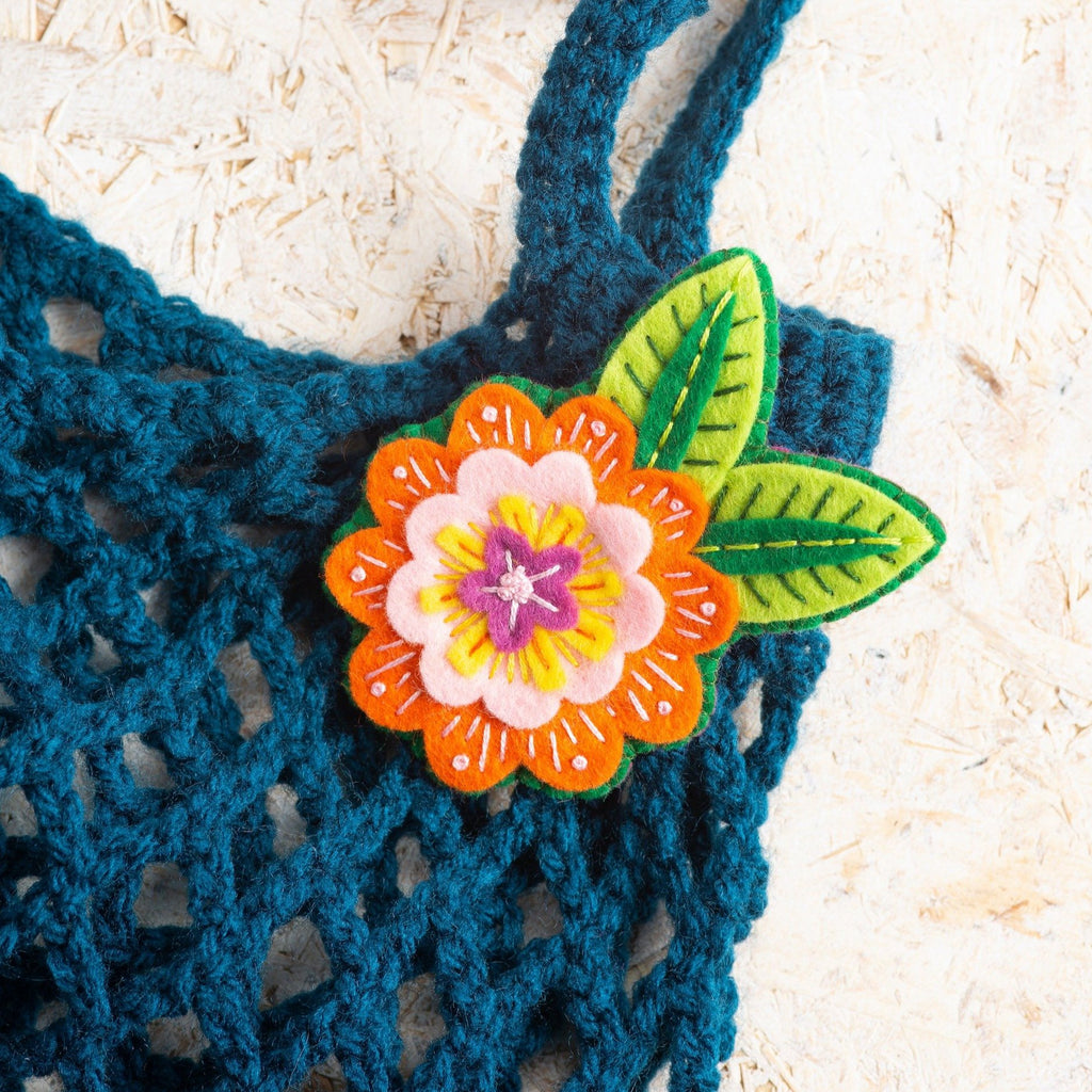 Margery flower brooch worn on blue crochet bag.