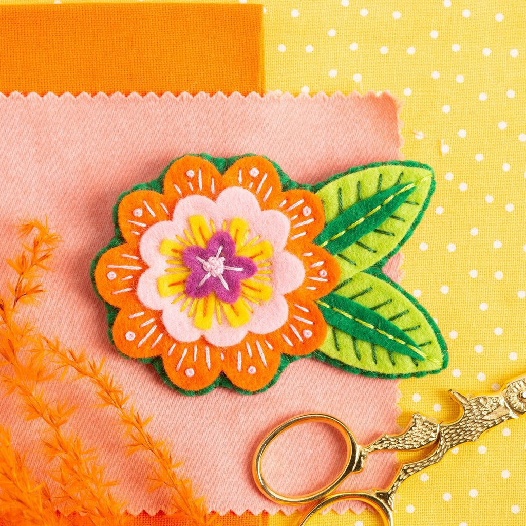 Margery Flower Brooch displayed on orange, yellow and peach background.