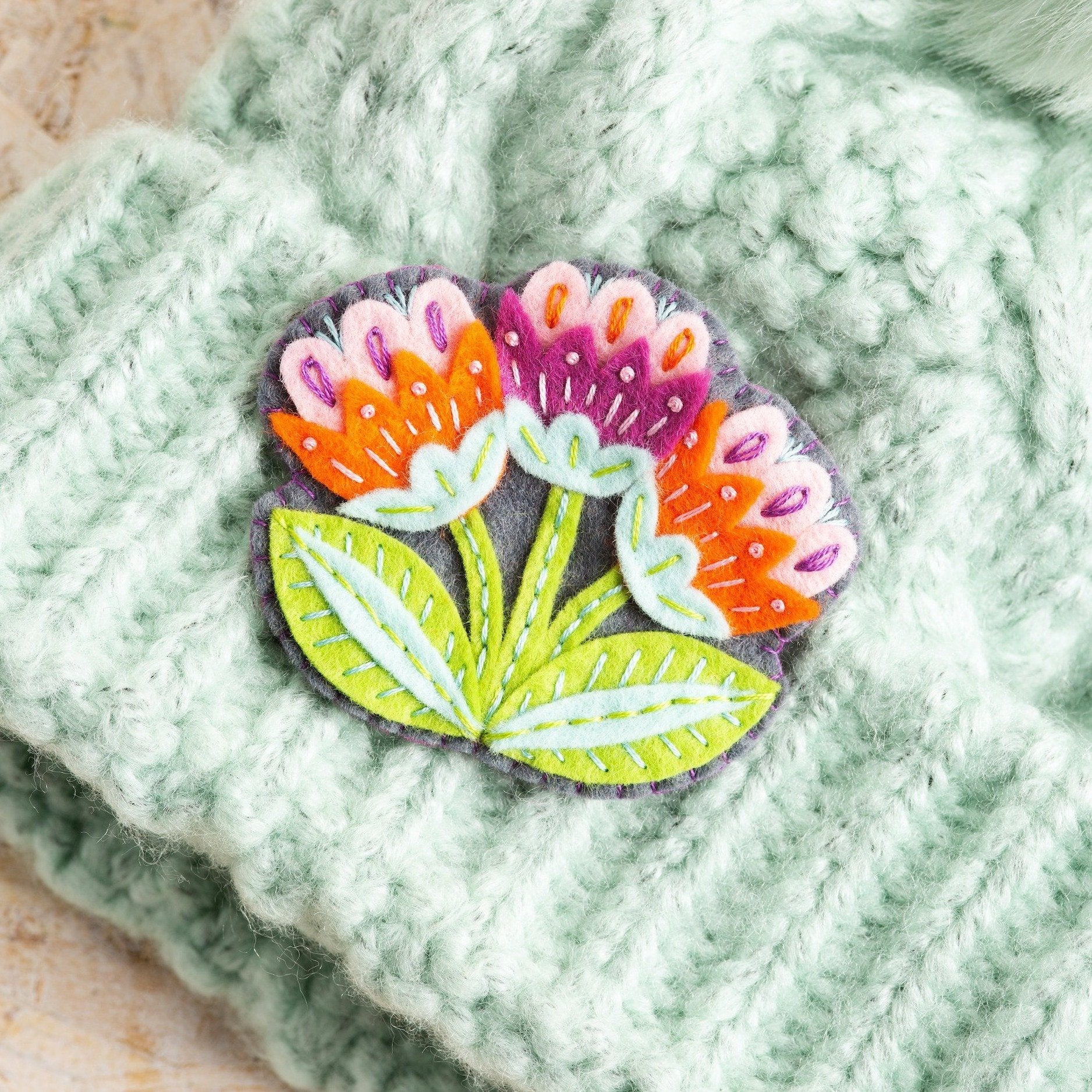 Marianne flower felt craft brooch won on mint green knitted hat.