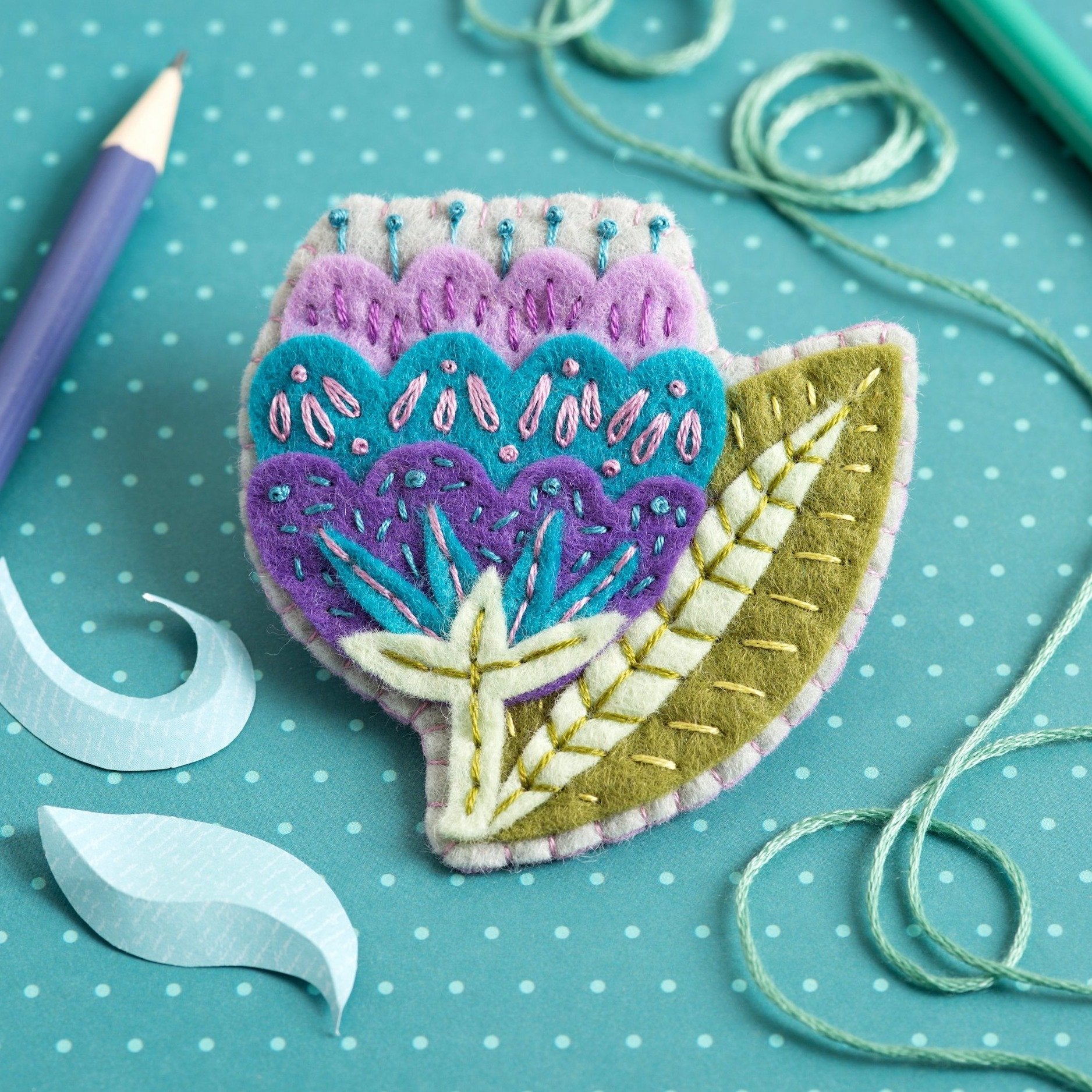 Vita flower felt brooch on teal background.